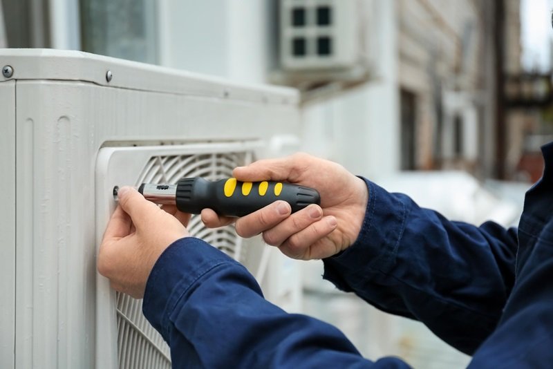technician working on outside air conditioning unit